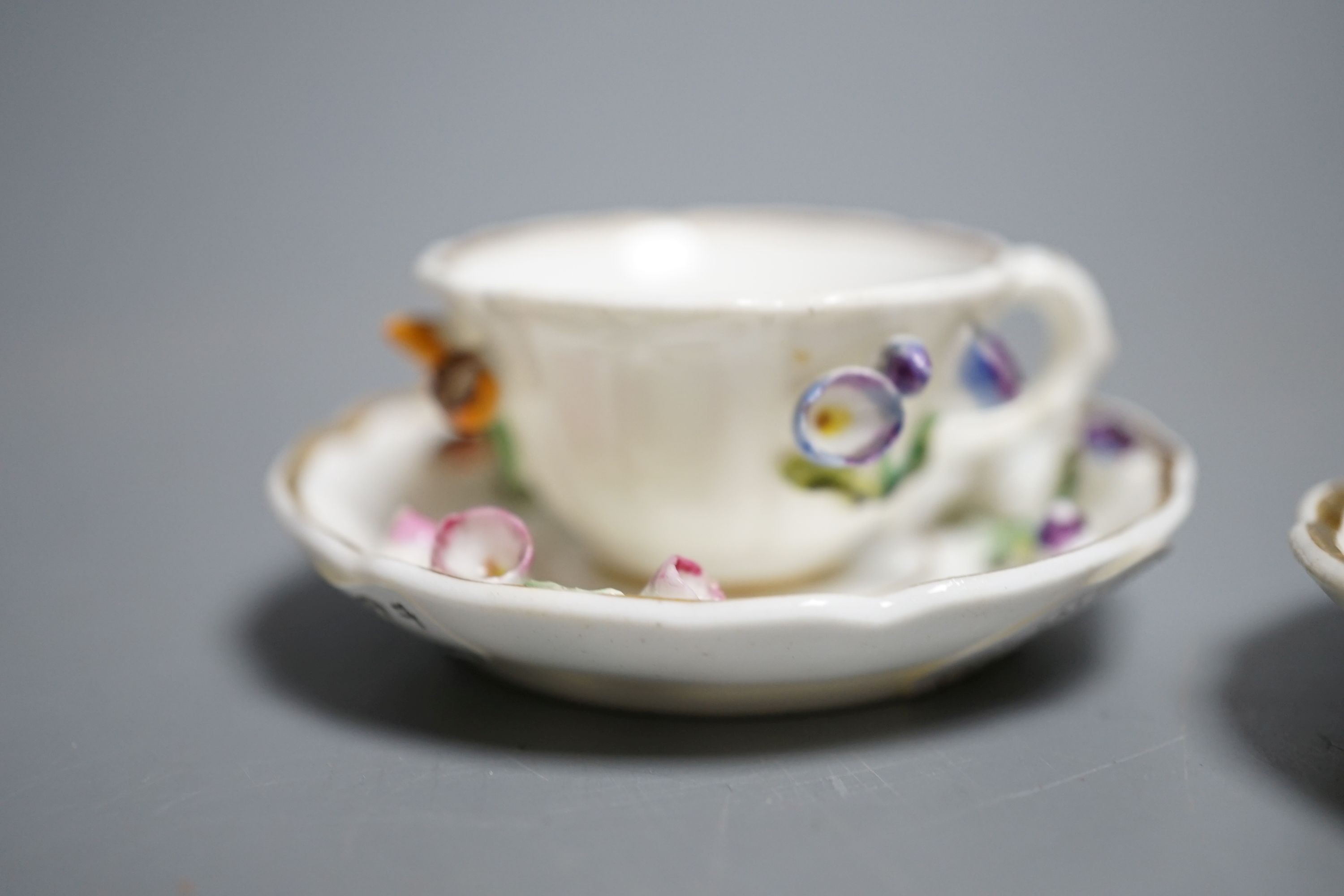 Two Rockingham miniature flower encrusted cups and saucers, c.1830. Provenance - Mona Sattin collection of miniature cups and saucers, collection no. 199 and 200.